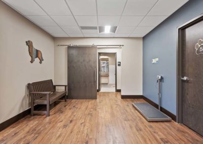 A hallway in an animal hospital with wooden floors and a bench.
